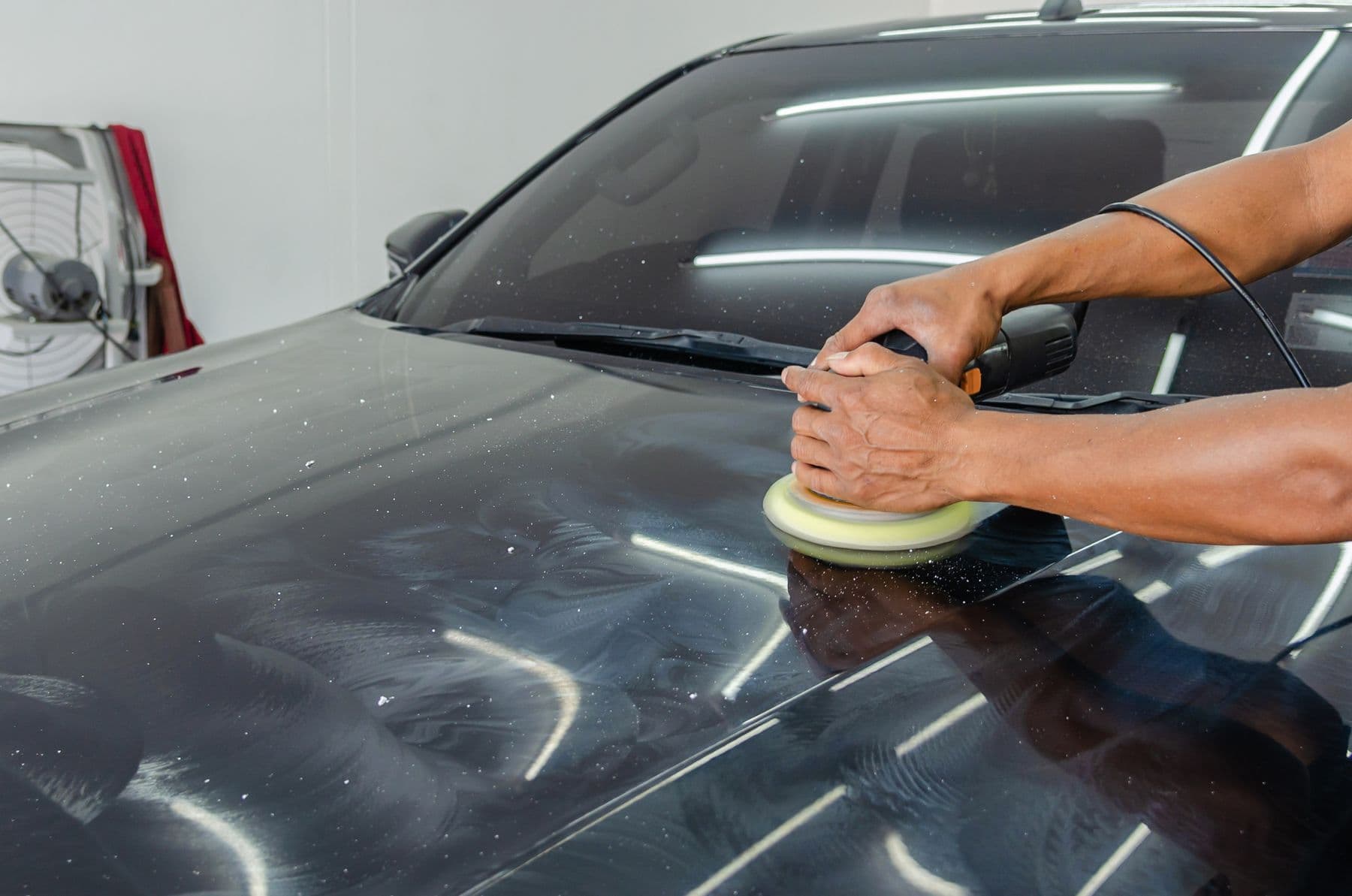 Lucidatura del cofano di un'auto nera in officina